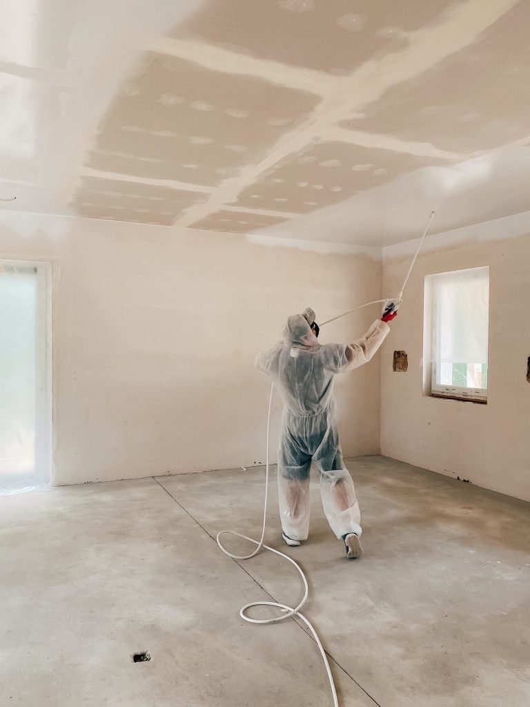 Man paints ceiling with a paint sprayer